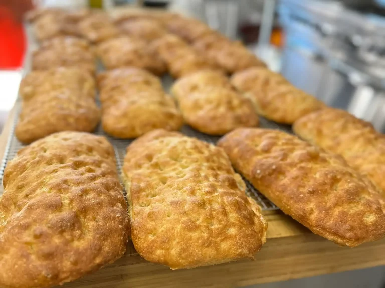 Tray of crusty round bread rolls cooling on a wire rack in a bakery