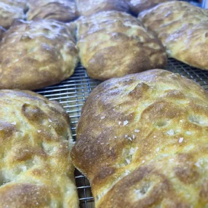 Marvelli focaccia bread cooling on a metal wire rack baked to a golden brown