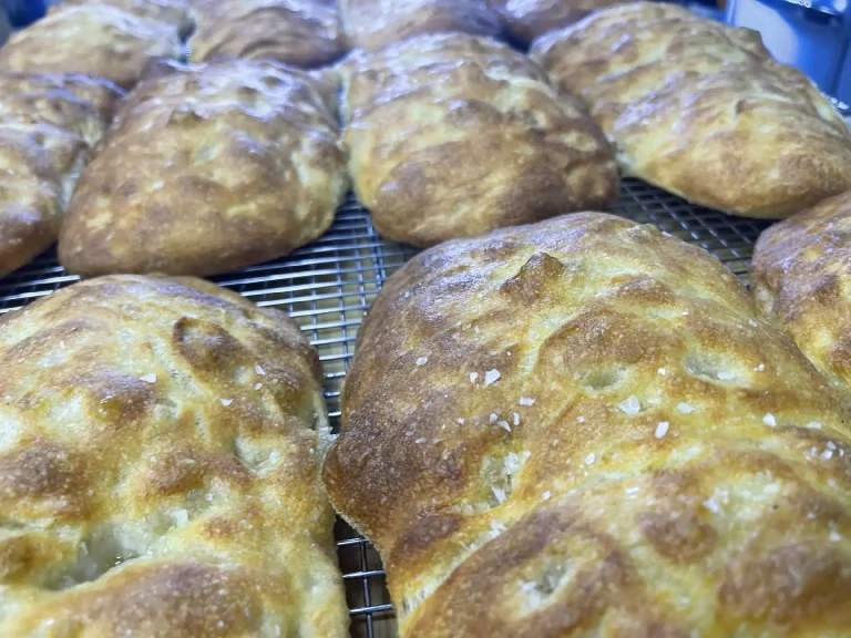 Golden brown marvelli focaccia bread cooling on a metal wire rack with a light sprinkling of salt crystals