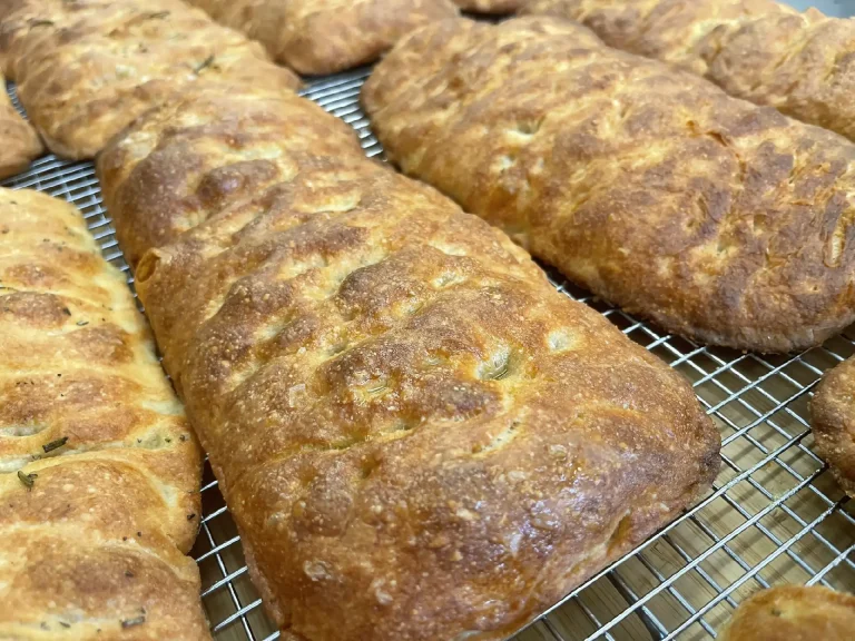 Golden brown crusty bread rolls arranged on a cooling rack